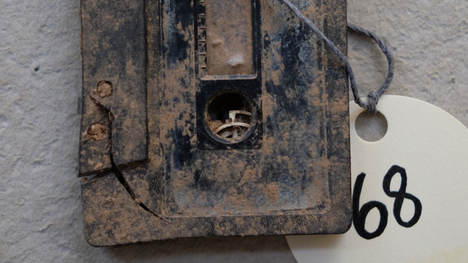 Close up of a cassette tape caked in mud with a tag that says "68" attached to it