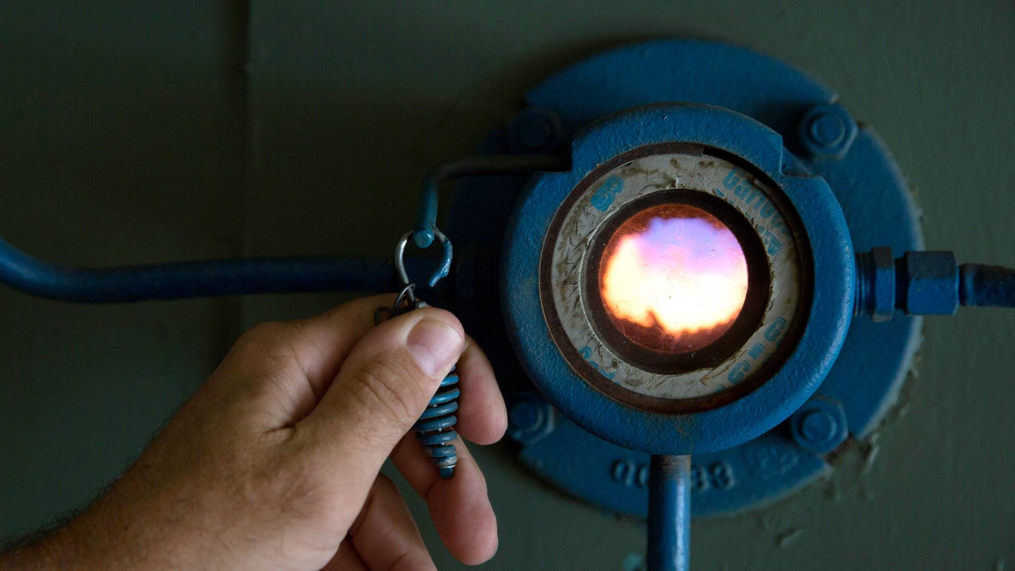A hand pulls on a lever to open a viewport into a natural gas boiler fire tube